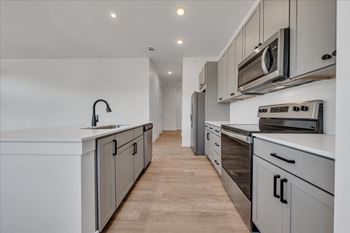 A modern kitchen with a white countertop and stainless steel appliances at Luxe 360 on Centerpointe Apartments, Virginia